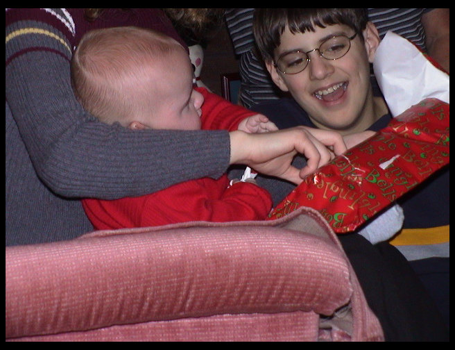 Now Tyler is helping Logan open a present.