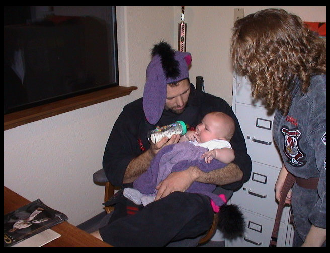 Mr. Graves giving Logan a bottle, Ms. McKennon leaning in.