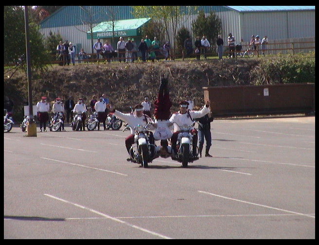 Here you can see two men driving, one man holding the cycles together, and another doing a headstand on his back.